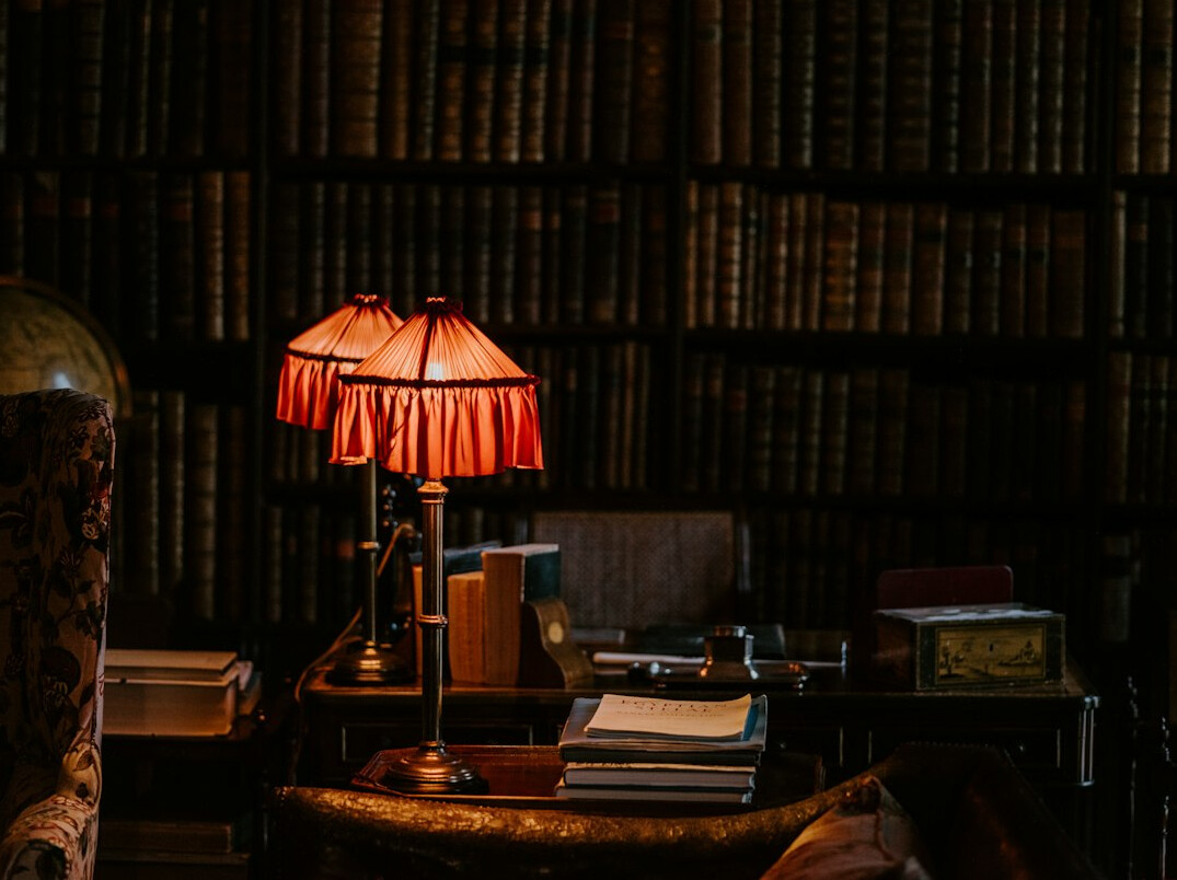 Dim archive library with old leather-bound books and a warm reading lamp