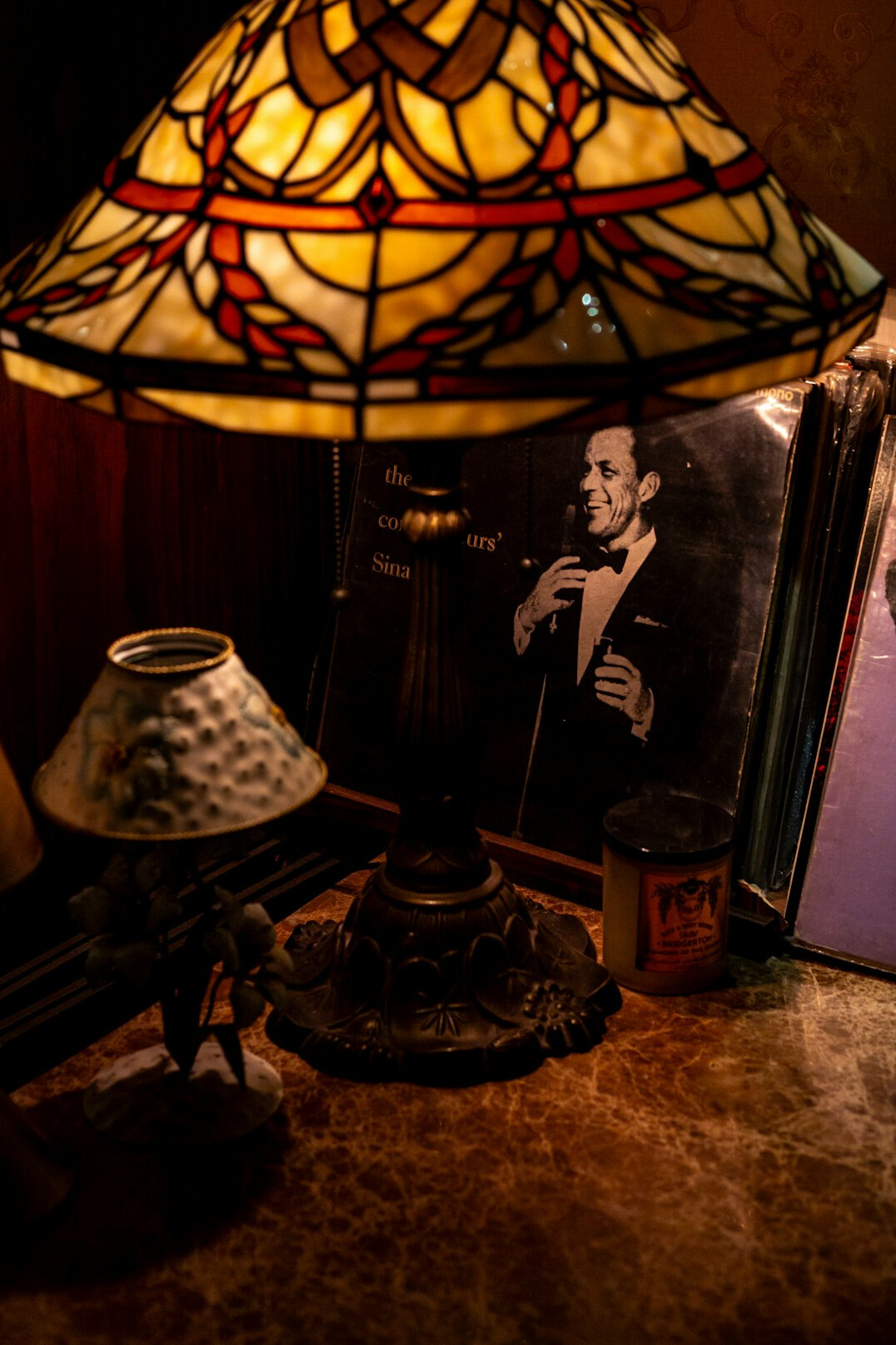 Stack of detective and mystery novels on a wooden table with a reading lamp